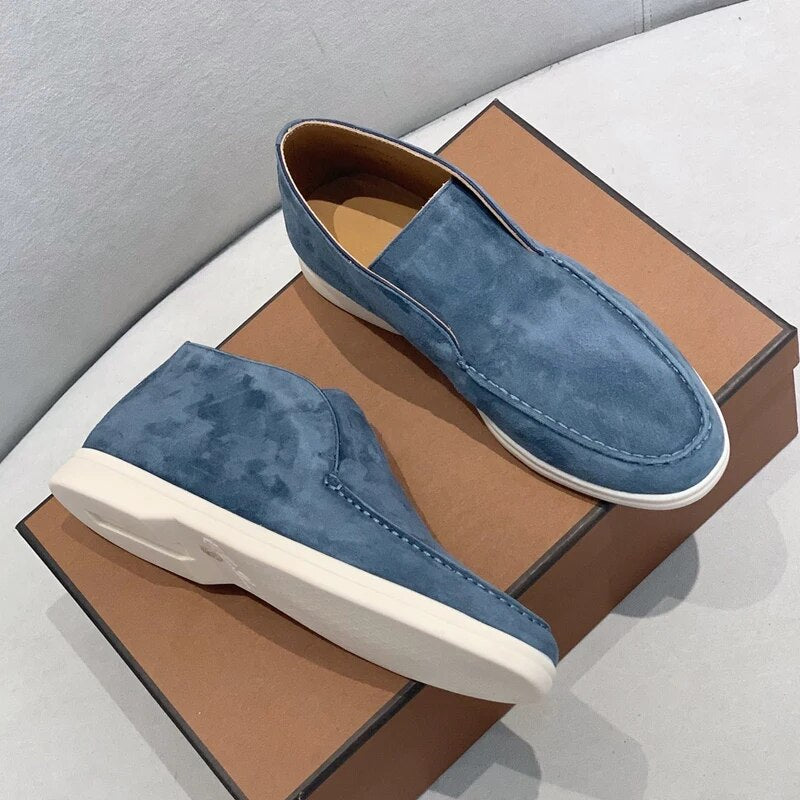 Chaussures mocassins en daim bleu pour homme sur boîte marron, semelles blanches, style décontracté et élégant, parfaites pour la mode masculine.