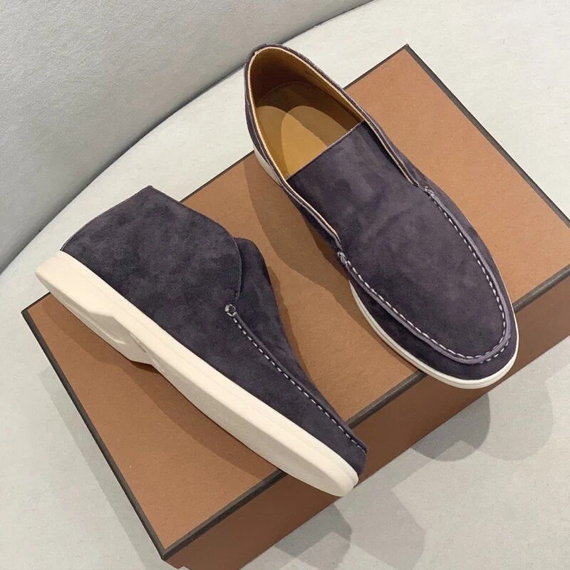 Mocassins en daim bleu marine pour homme sur boîte marron, semelles blanches, style élégant et moderne, chaussures décontractées tendance.