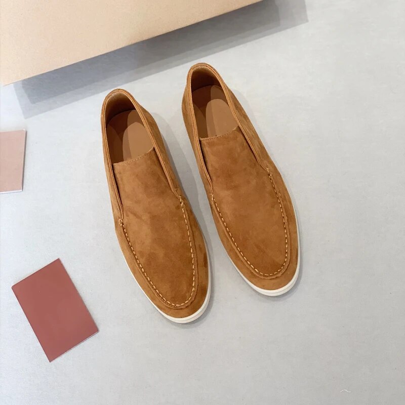 Mocassins en daim marron clair pour homme sur fond gris, style décontracté et élégant, chaussures sans lacets, semelle blanche contrastante.