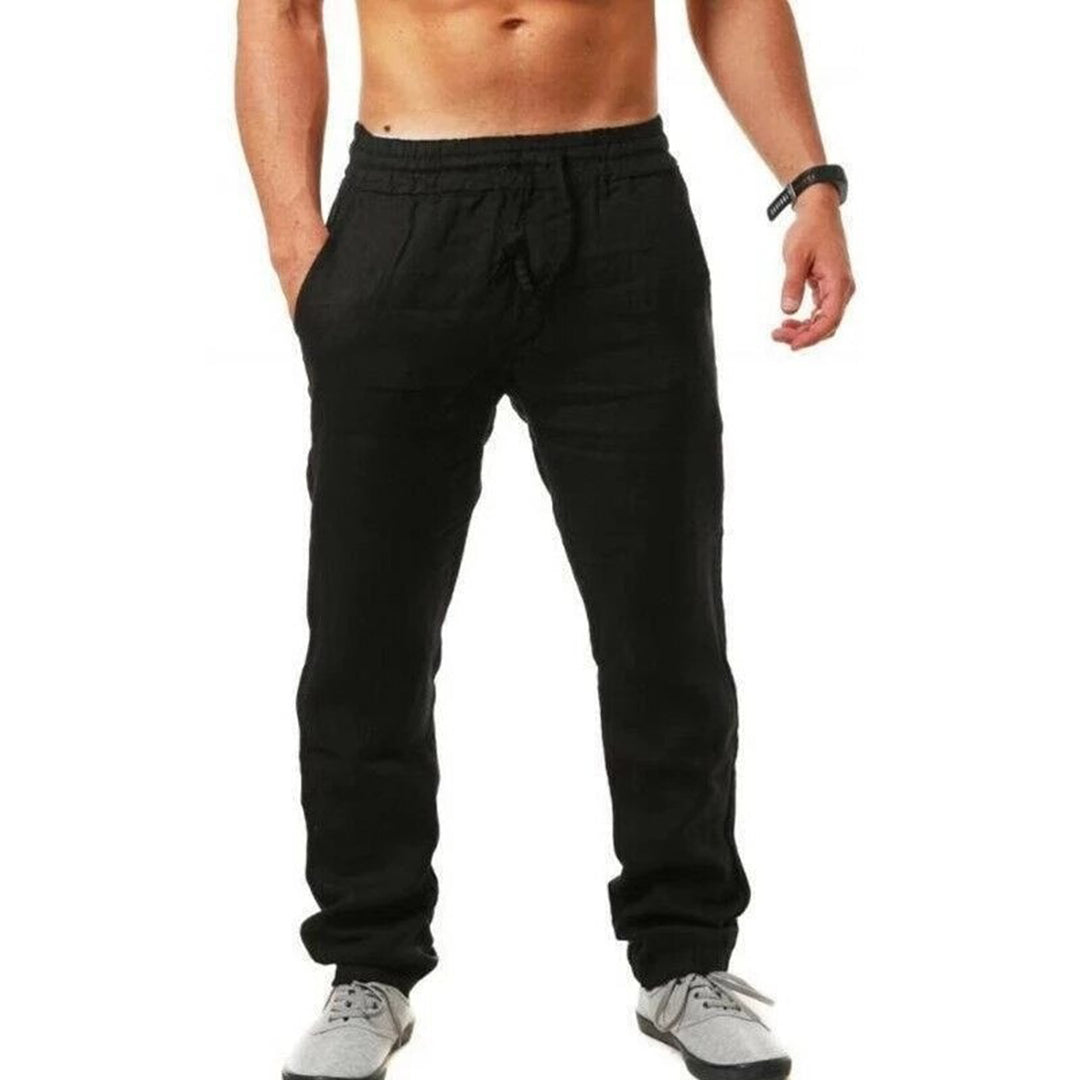 Homme portant un pantalon de jogging noir, taille élastique, avec des baskets grises. Mode décontractée, vêtements de sport pour hommes.