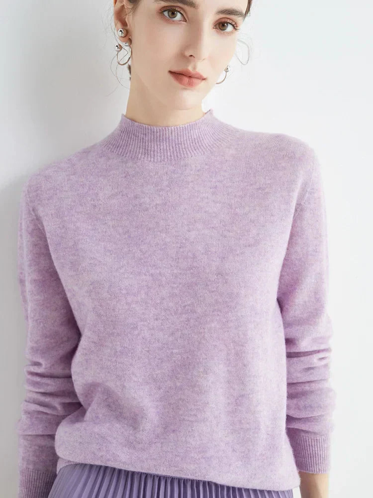 Femme portant un pull en cachemire lavande, manches longues, col rond, avec jupe plissée violette. Mode élégante et tendance automne-hiver.