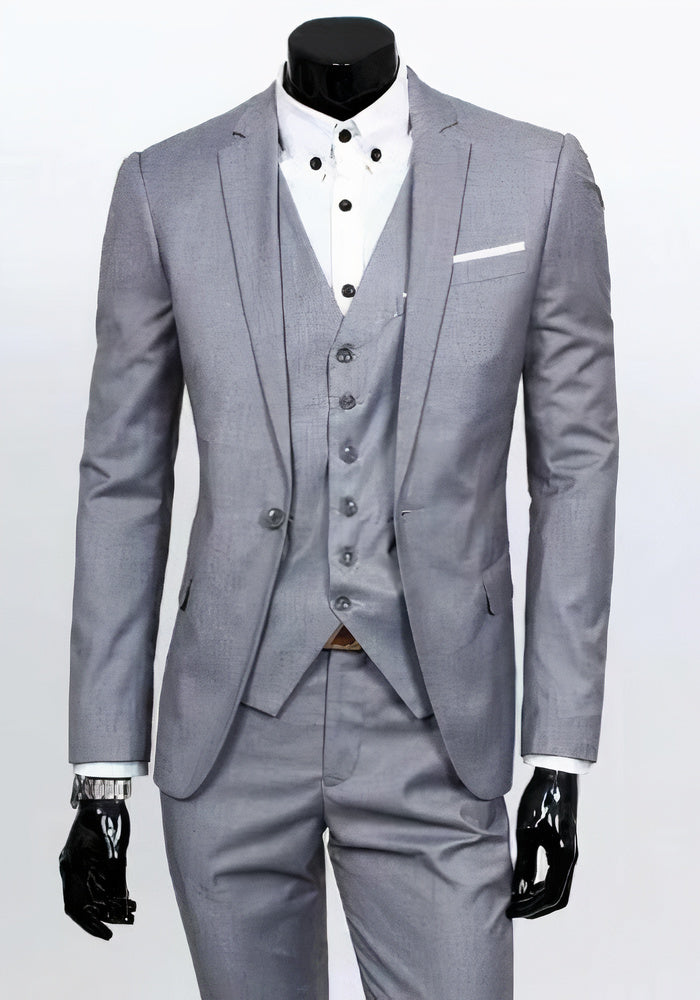 Costume gris élégant pour homme avec gilet assorti, chemise blanche à boutons noirs et pochette blanche, idéal pour mariage ou événement formel.