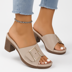 Sandales à talons beiges avec boucle dorée, portées avec un jean délavé. Chaussures élégantes pour femme, tendance mode estivale.