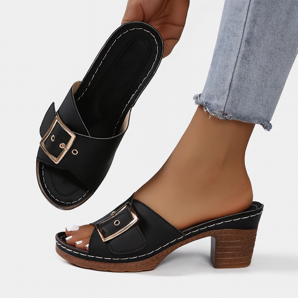 Sandales à talons noires avec boucle dorée, portées avec un jean. Chaussures élégantes pour femme, mode estivale, confort et style.