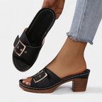 Sandales à talons noires avec boucle dorée, portées avec un jean. Chaussures élégantes pour femme, mode estivale, confort et style.