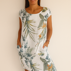 Robe d'été blanche à motifs floraux verts et orange, manches courtes, poches latérales, portée par une femme souriante. Mode féminine estivale.