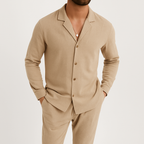 Homme portant un ensemble beige élégant, chemise à col ouvert et pantalon assorti, style décontracté chic, mode masculine moderne.