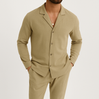 Homme portant un ensemble beige élégant, chemise à col ouvert et pantalon assorti, style décontracté chic, mode masculine moderne.