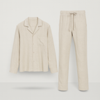 Pyjama en lin beige pour homme, composé d'une chemise à manches longues avec poche poitrine et d'un pantalon à cordon, sur fond blanc.