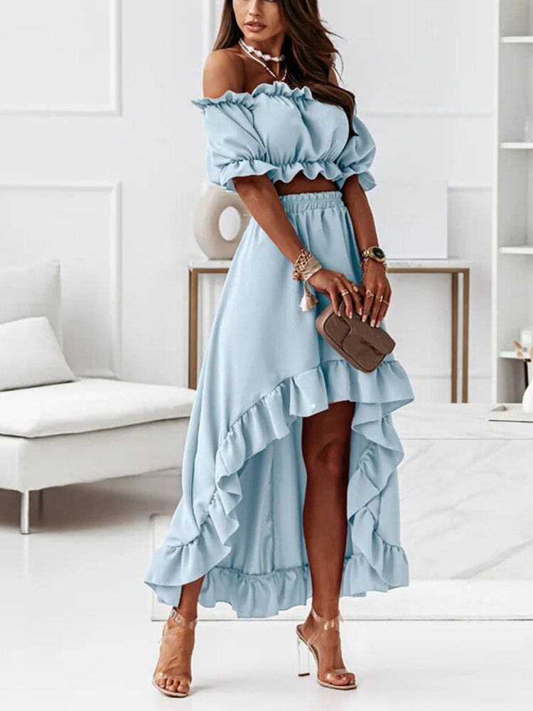Femme en robe bleue à volants, épaules dénudées, posant dans un salon moderne. Mode élégante, tenue estivale, style chic.