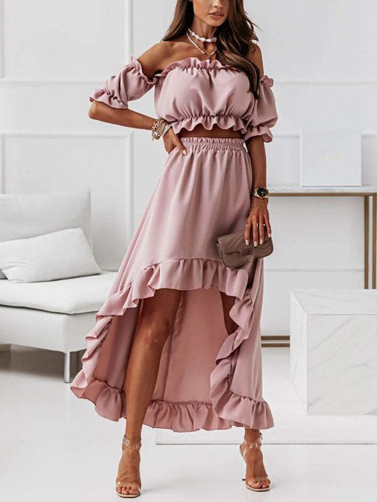 Robe rose à volants, épaules dénudées, portée par une femme dans un salon moderne. Mode élégante, tenue estivale, style chic et tendance.