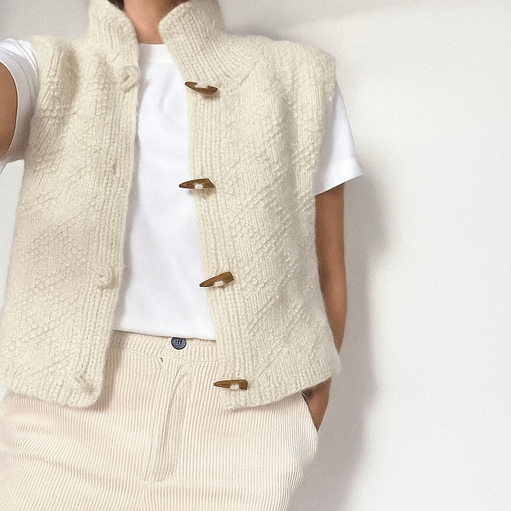 Gilet en laine beige avec boutons en bois, porté sur un t-shirt blanc. Mode automne-hiver, style décontracté et élégant.
