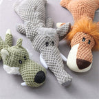 Trois peluches d'animaux en tricot: un crocodile gris, un loup vert et un lion orange, posées sur une surface grise. Jouets doux pour enfants.