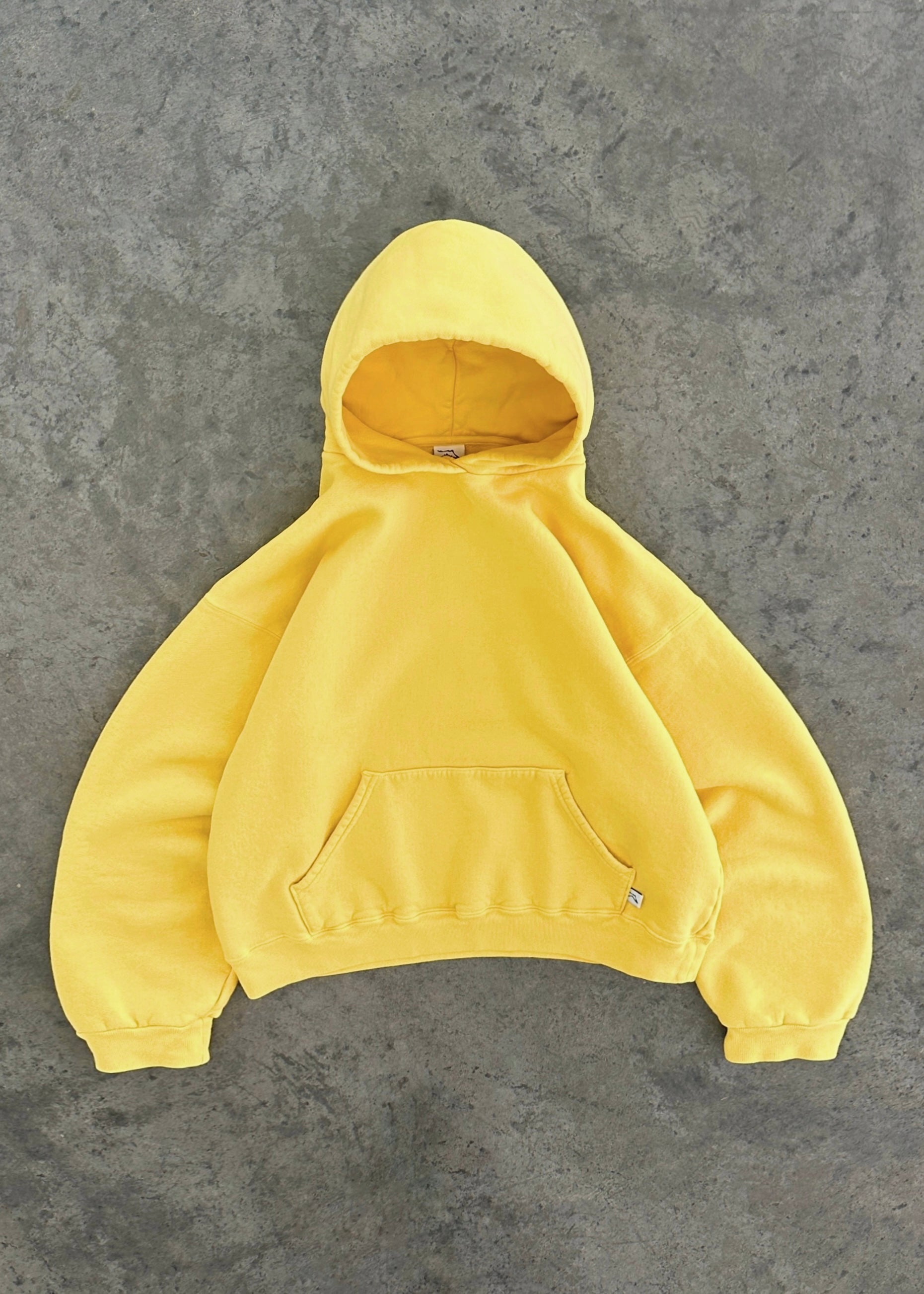 Sweat à capuche jaune vif sur fond gris, style décontracté, poche kangourou, manches longues, tendance mode urbaine, vêtement confortable.