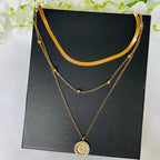 Collier multi-rangs doré avec pendentif rond floral, chaînes fines et perles, sur fond noir. Bijoux élégants, tendance mode féminine.