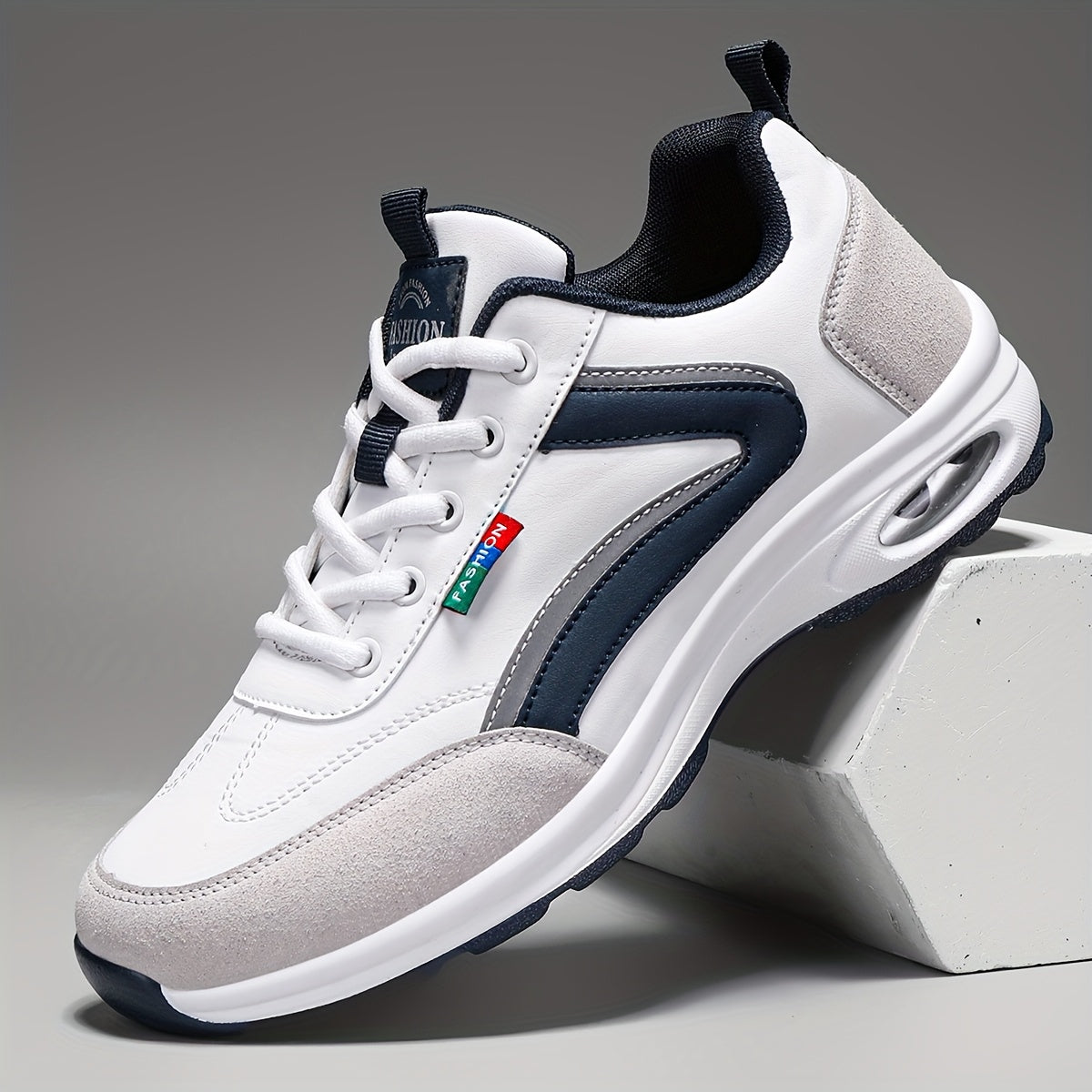 Chaussure de sport blanche et bleue avec semelle épaisse, lacets blancs, détails en cuir, posée sur un cube blanc. Idéale pour le running et le fitness.