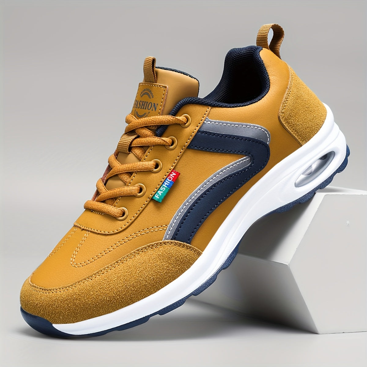 Chaussure de sport jaune moutarde avec semelle blanche, détails bleu marine, lacets marron, et logo coloré, posée sur un support blanc.