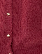Cardigan en laine rouge avec boutons dorés, texture douce et chaude, mode automne-hiver, vêtement élégant pour femme, style chic et confortable.