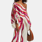 Femme portant une combinaison asymétrique à rayures rouges et roses, tenant un sac à main marron. Mode élégante, tenue chic, style moderne.