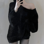 Femme en pull noir en laine, épaules dénudées, prenant un selfie. Mode hiver, style décontracté, tendance vêtements chauds.