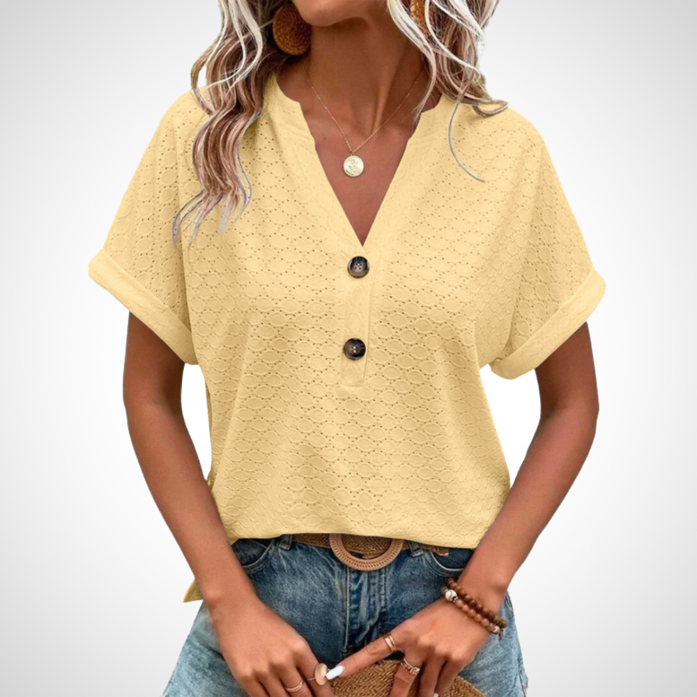 Blouse jaune à manches courtes avec boutons noirs, col en V, portée par une femme. Style décontracté, mode féminine, tenue estivale tendance.