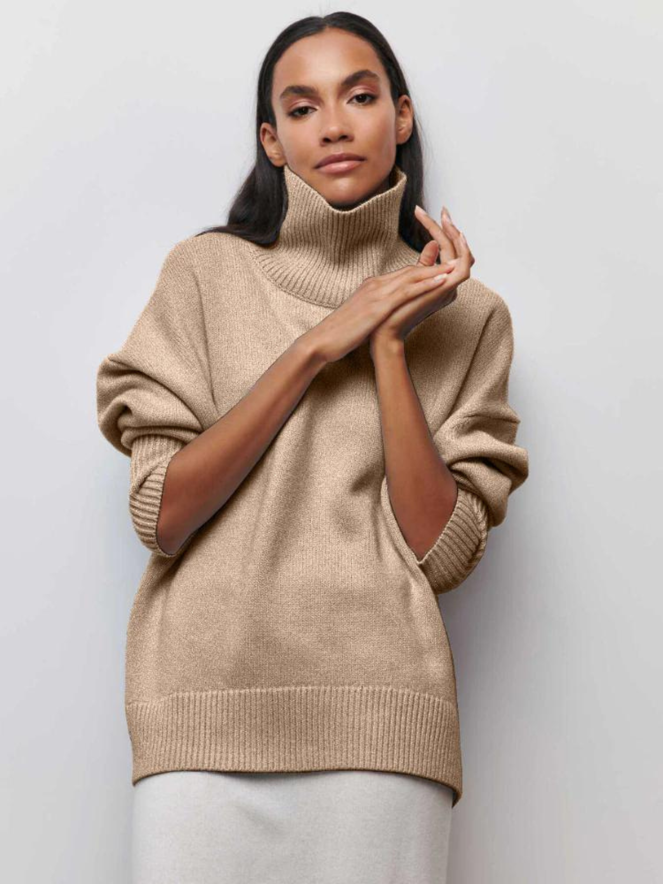 Femme portant un pull en laine beige à col roulé, manches longues, style décontracté. Mode automne-hiver, tendance vêtements chauds élégants.