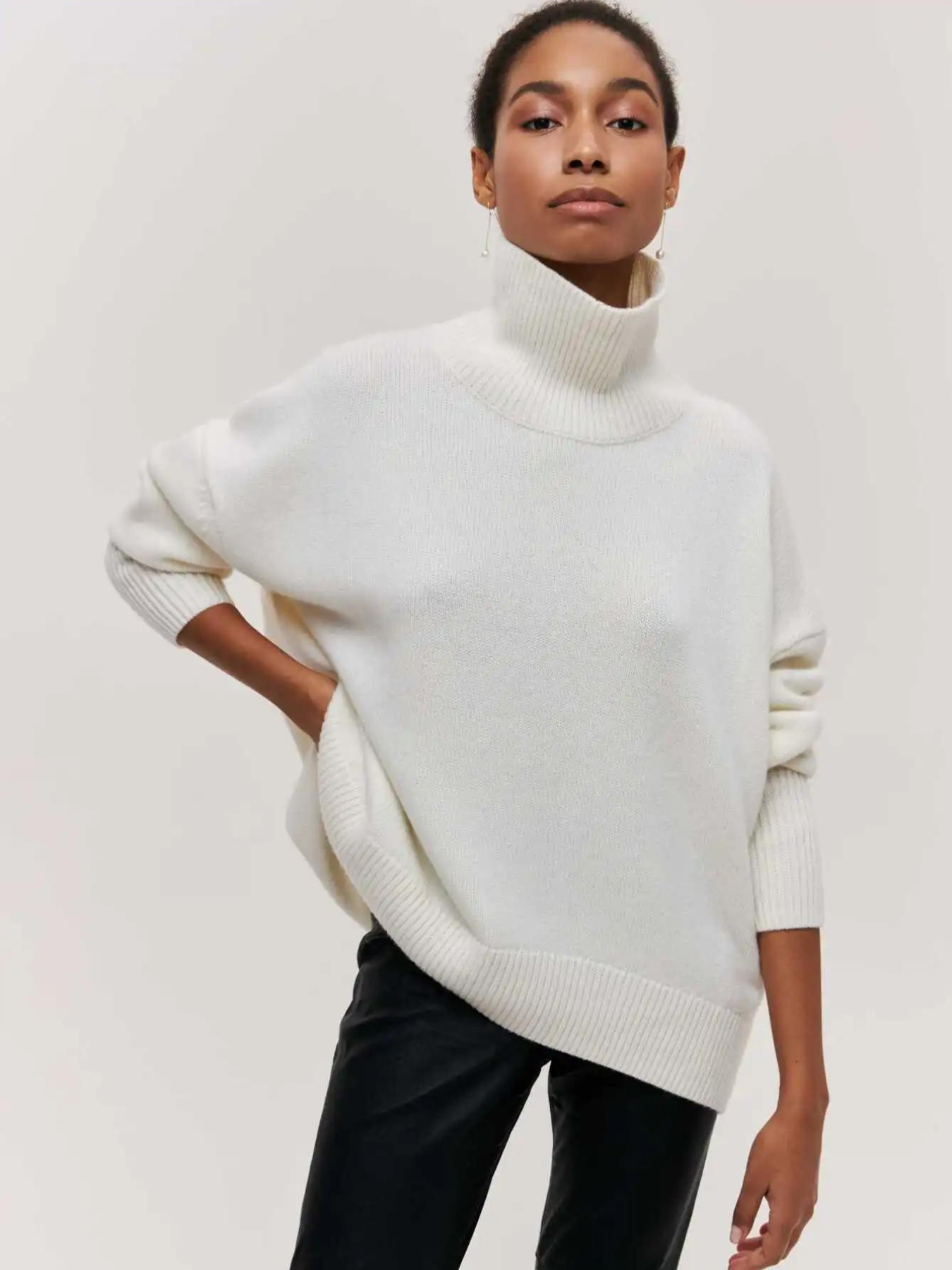 Femme portant un pull blanc à col roulé, manches longues, style décontracté, sur fond neutre. Mode automne-hiver, tendance élégante et confortable.