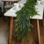 Guirlande de sapin réaliste sur table blanche, décor de Noël élégant avec tasses à café, ambiance festive et naturelle, décoration intérieure moderne.