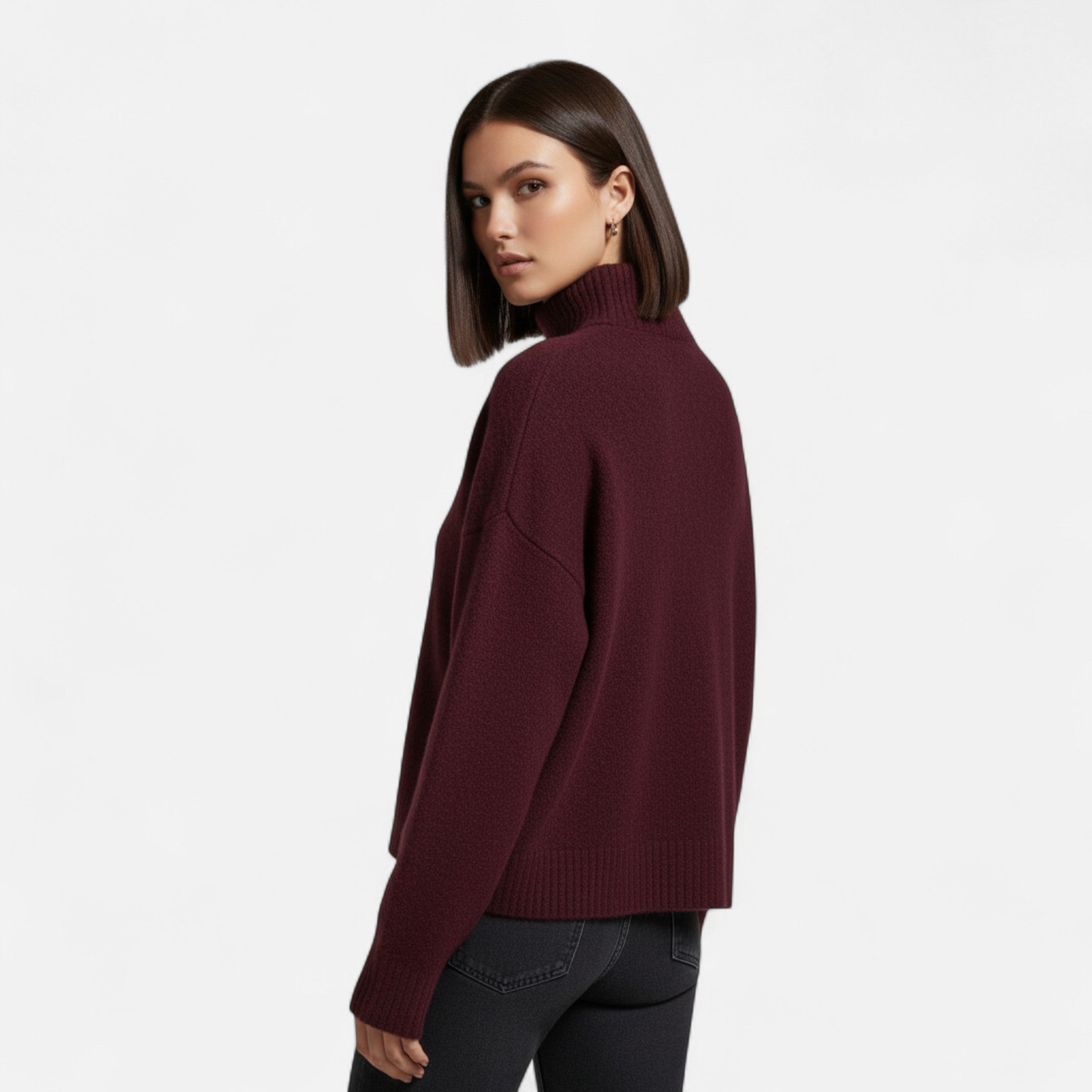 Jeune femme portant un pull bordeaux à col roulé, posant de profil. Mode automne-hiver, style élégant et moderne. Fond blanc minimaliste.
