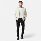 Homme portant un cardigan blanc, t-shirt blanc et pantalon noir, posant debout. Mode masculine élégante, tenue décontractée chic.