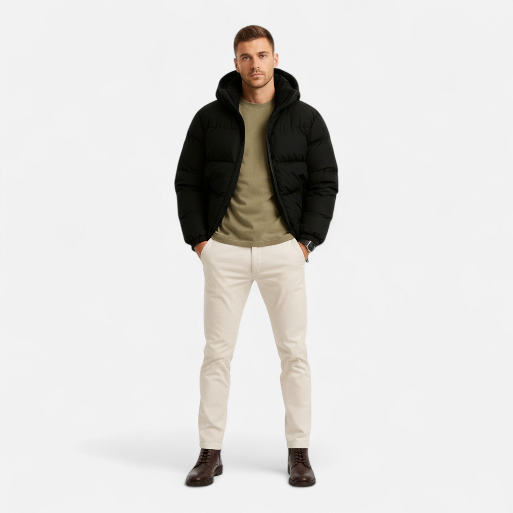Homme portant une doudoune noire, pull kaki, pantalon beige et bottes marron. Mode masculine hiver, tenue décontractée élégante.