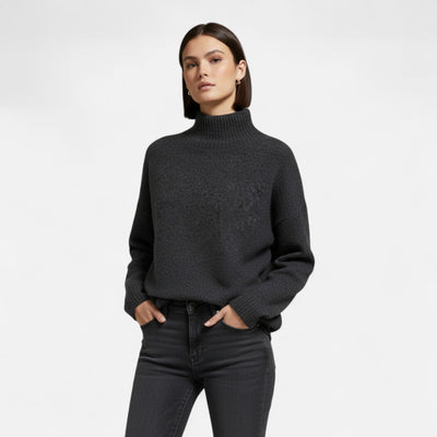 Femme portant un pull noir à col roulé, manches longues, avec un jean noir. Mode automne-hiver, style décontracté et élégant.