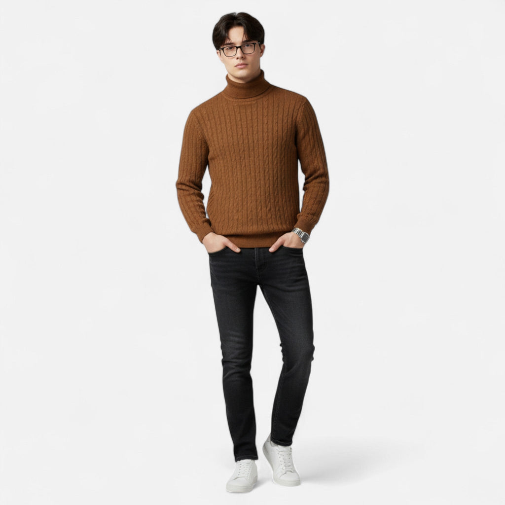 Homme portant un pull marron à col roulé, jeans noirs et baskets blanches, posant sur fond blanc. Mode masculine automne-hiver, style décontracté.