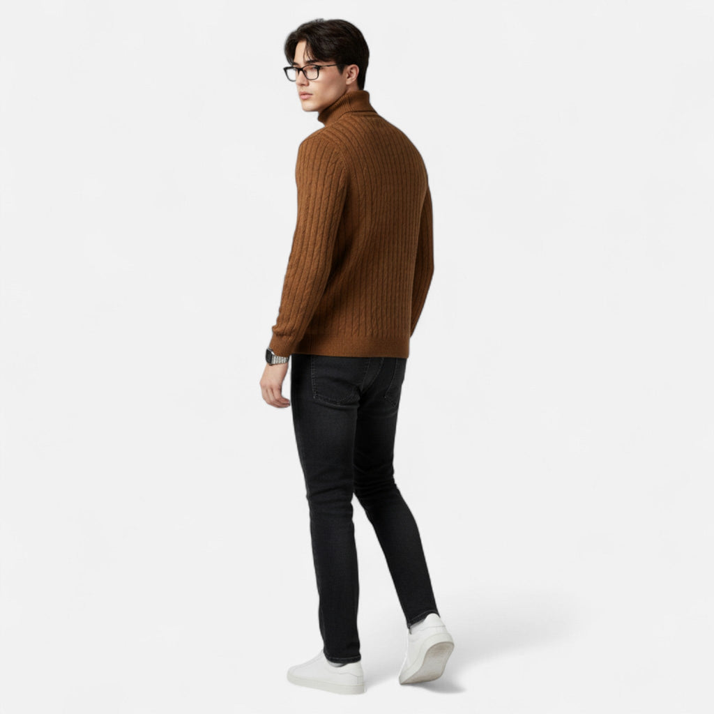 Homme portant un pull marron à col roulé, jeans noirs et baskets blanches, regardant en arrière. Mode masculine automne-hiver, style décontracté.