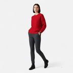 Femme portant un pull rouge en maille torsadée, pantalon gris et bottines noires. Mode automne-hiver, tenue élégante et décontractée.