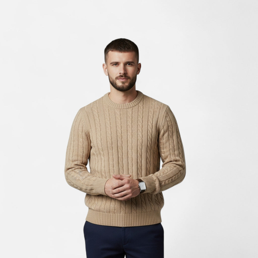 Homme portant un pull en laine beige torsadé, manches longues, sur fond blanc. Mode masculine élégante, style automne-hiver.