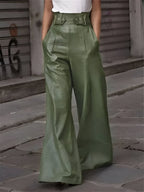 Pantalon large en cuir vert olive, taille haute avec ceinture, porté par une personne en t-shirt blanc, sur fond de rue urbaine.