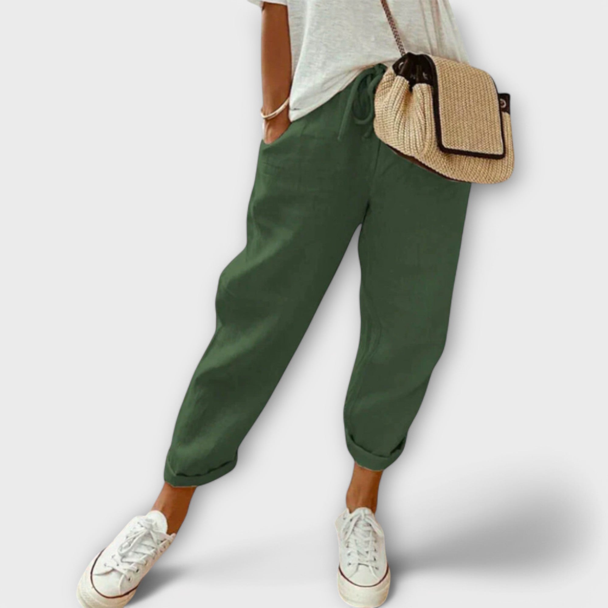 Pantalon vert décontracté pour femme, associé à un t-shirt blanc et des baskets blanches, sac en osier. Mode féminine, style décontracté.