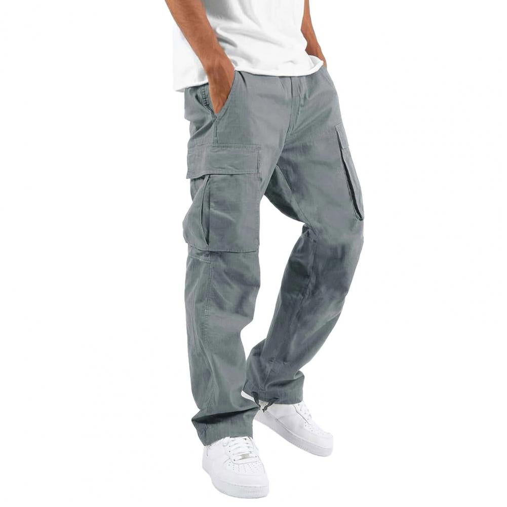 Pantalon cargo gris pour homme, poches multiples, style décontracté, porté avec des baskets blanches et un t-shirt blanc. Mode urbaine tendance.