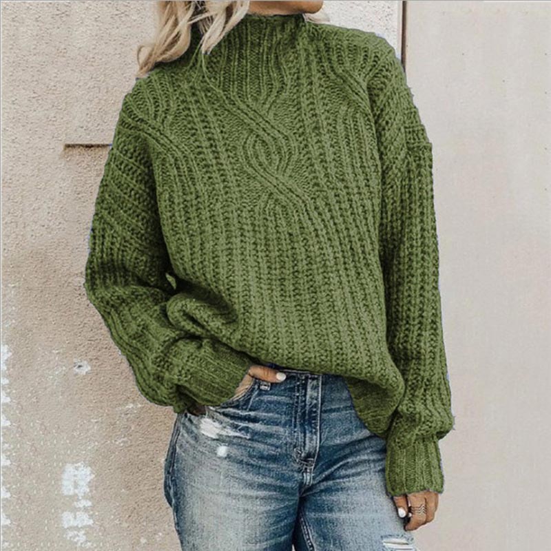 Femme portant un pull vert en tricot torsadé avec col roulé, associé à un jean décontracté. Mode automne-hiver, style confortable et tendance.