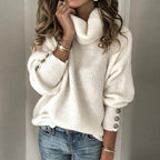Femme portant un pull blanc en laine à col roulé, manches longues avec boutons, associée à un jean bleu. Mode automne-hiver, style décontracté.