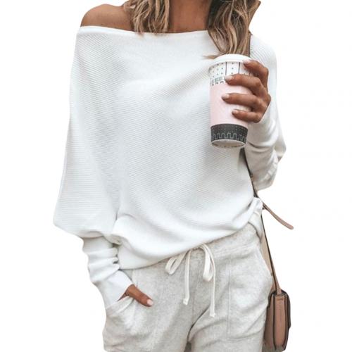 Femme en pull blanc décontracté, tenant un gobelet de café, portant un pantalon de jogging gris, style mode automne-hiver, look confortable et chic.