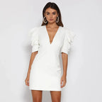 Robe blanche élégante à manches bouffantes, décolleté plongeant, portée par une femme. Mode féminine chic, tendance soirée, style moderne.