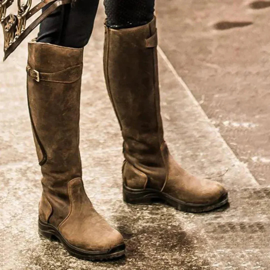 Bottes hautes en cuir marron sur sol en béton, style équestre, mode automne-hiver, chaussures robustes et élégantes pour homme ou femme.