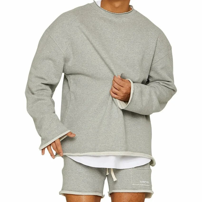 Homme portant un ensemble décontracté gris, sweat-shirt et short assortis, style moderne et confortable, mode masculine tendance.