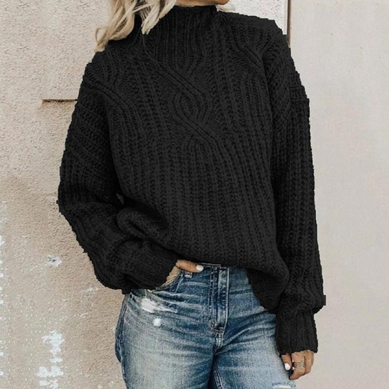 Femme portant un pull noir en tricot torsadé avec un col montant, associée à un jean décontracté. Mode automne-hiver, style décontracté chic.