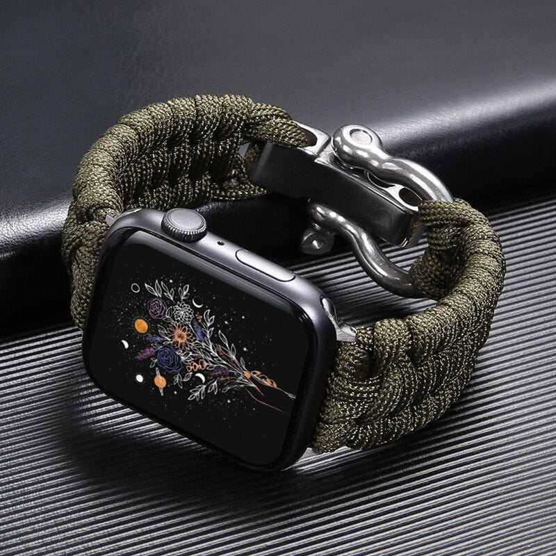 Montre intelligente avec bracelet en paracorde vert, écran affichant un motif floral coloré, posée sur une surface noire texturée.