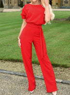 Combinaison rouge élégante pour femme, manches courtes, ceinture à nouer, portée dans un jardin. Mode féminine chic, tenue estivale tendance.