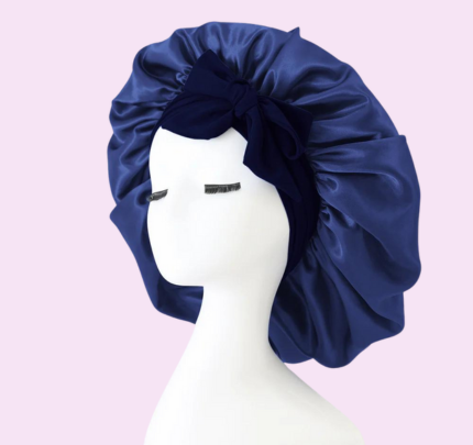 Mannequin portant un bonnet en satin bleu avec nœud, fond rose. Accessoire de mode pour cheveux, protection nocturne, style élégant.