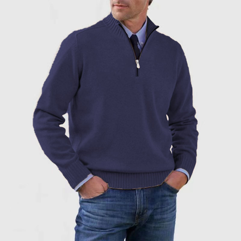 Homme portant un pull bleu marine à col zippé, manches longues, sur une chemise bleue, avec un jean décontracté. Mode masculine élégante et moderne.